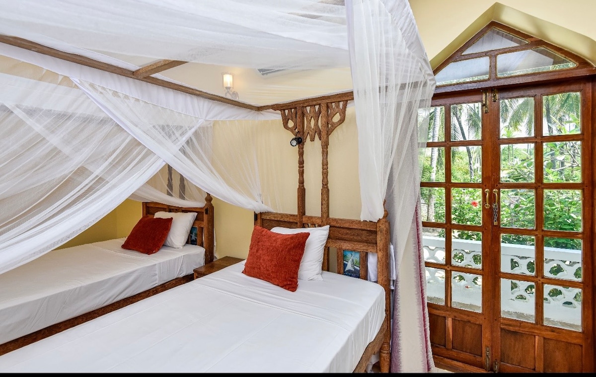 Twin bedroom with carved headboards and arched garden window